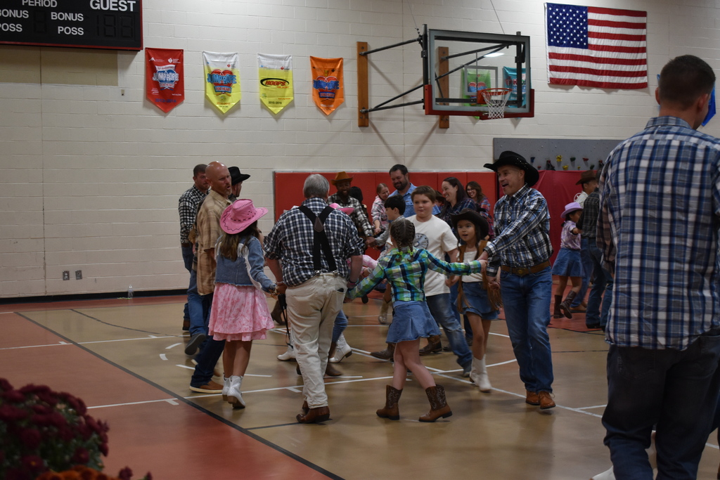 Students and their parents dance in a circle at the hoe down.  