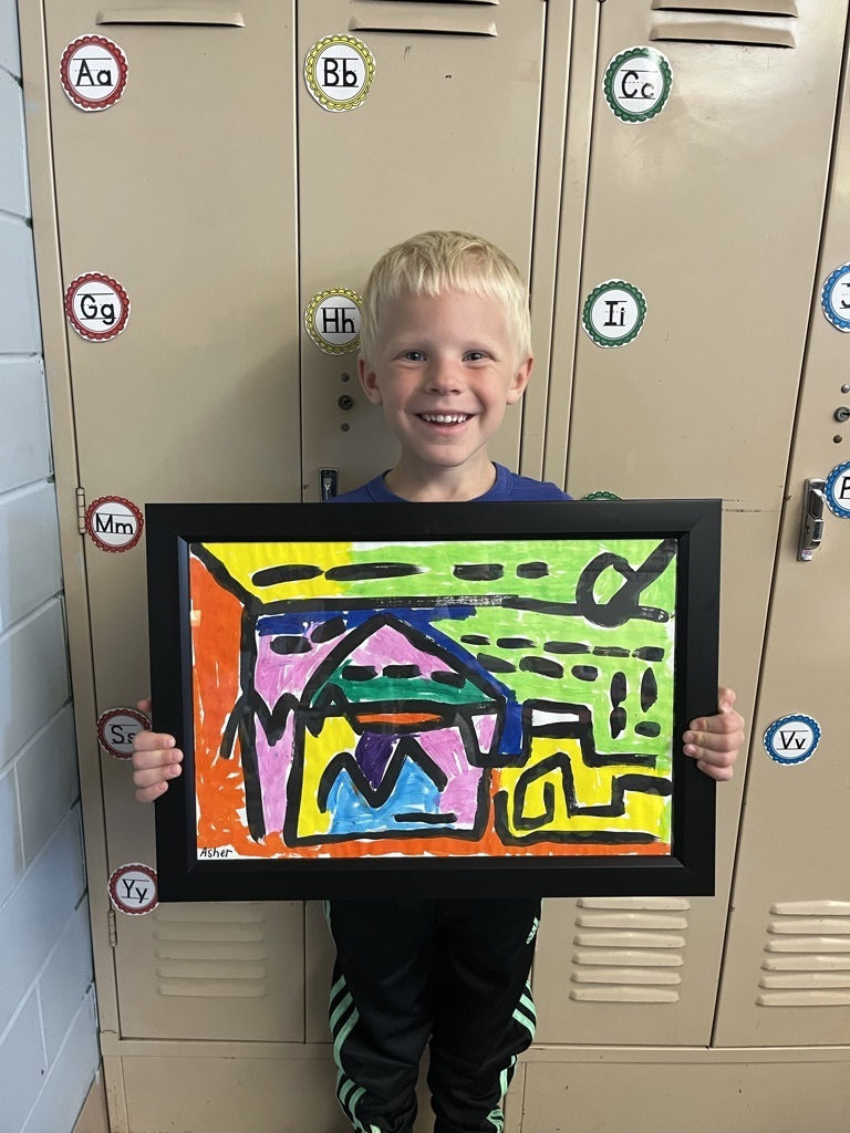 Broadway student poses with their framed artwork. 