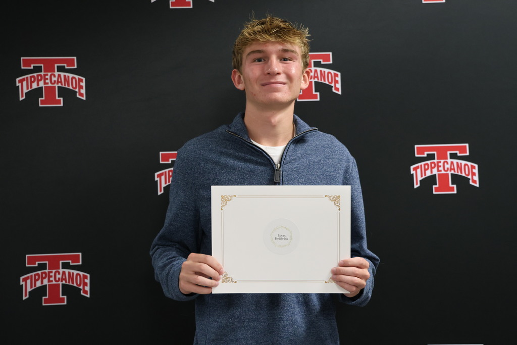 Student holding certificate after being honored at BOE meeting.