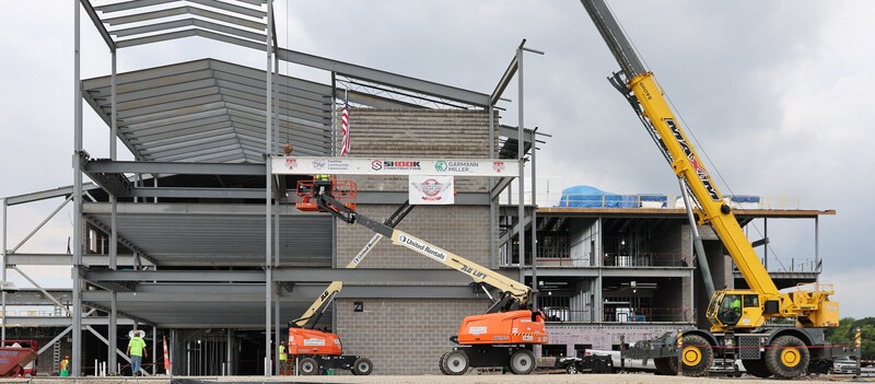 The steel beam with student signatures gets moved into place.