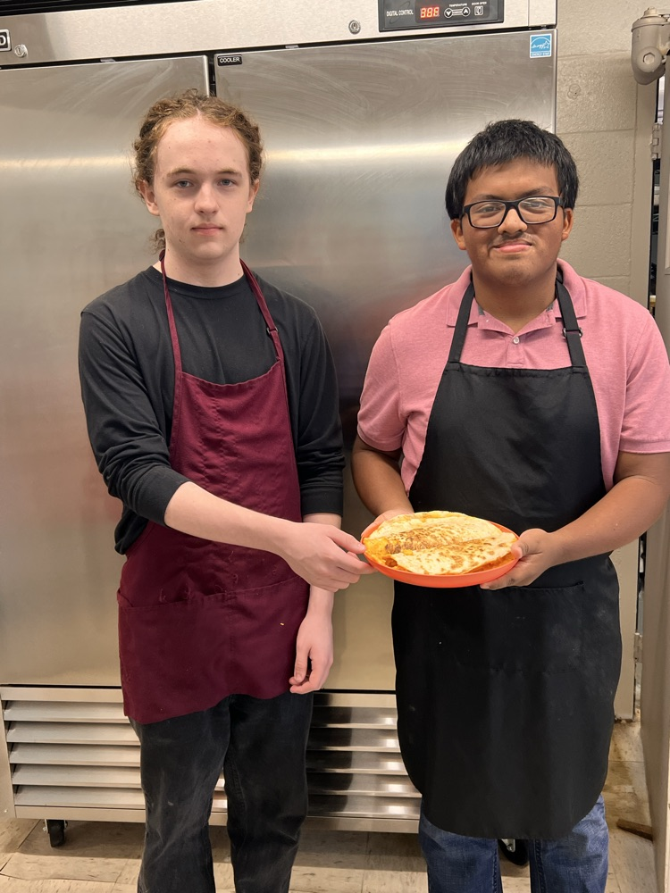 Students posing with finished dishes in Culinary class. 