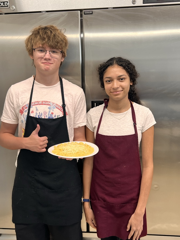 Students posing with finished dishes in Culinary class. 