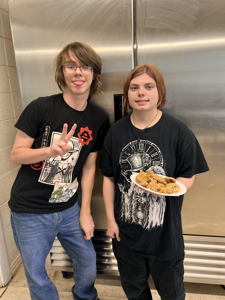 Students posing with finished dishes in Culinary class. 