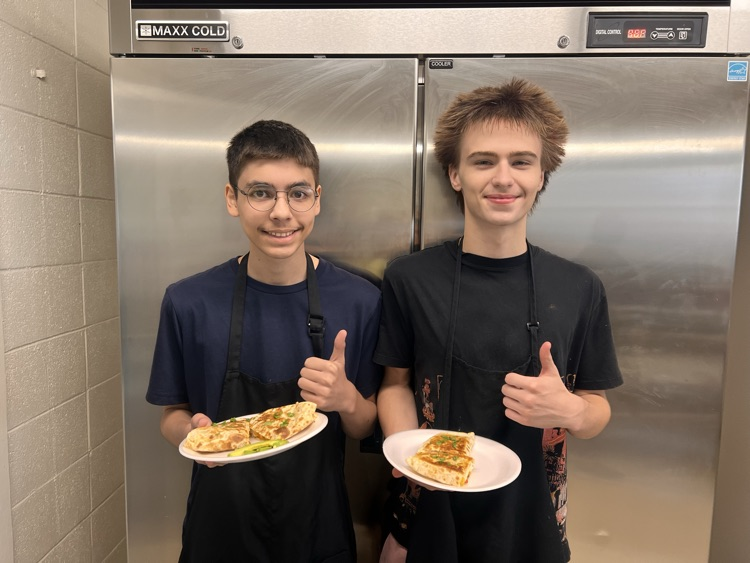 Students posing with finished dishes in Culinary class. 