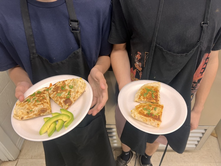 Students posing with finished dishes in Culinary class. 
