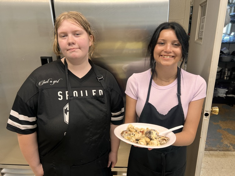 Students posing with finished dishes in Culinary class. 