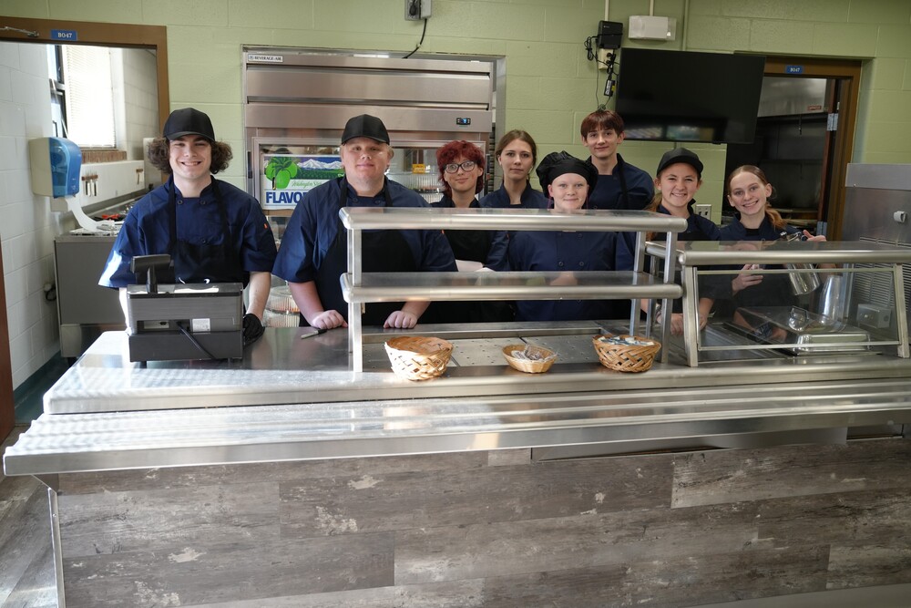 Culinary Arts students stand behind Bistro 555's counter and smile in preparation for the class-run restaurant to open for the 2026-2027 school year