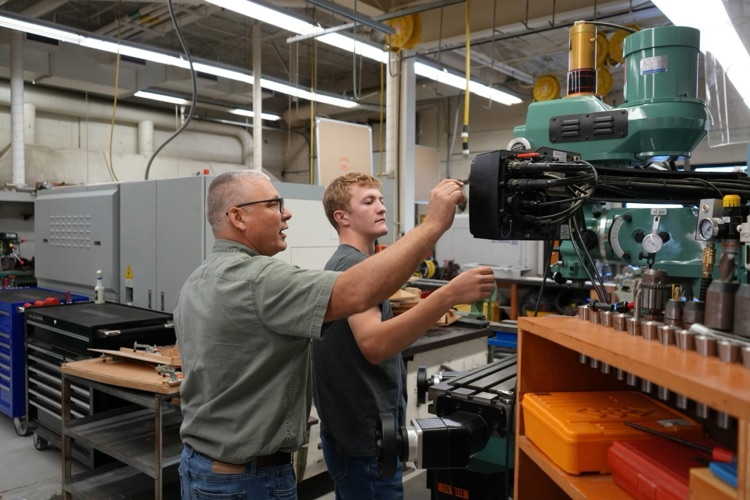 student and teacher working on machine