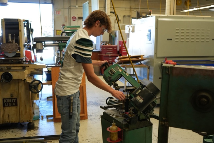 student cutting metal