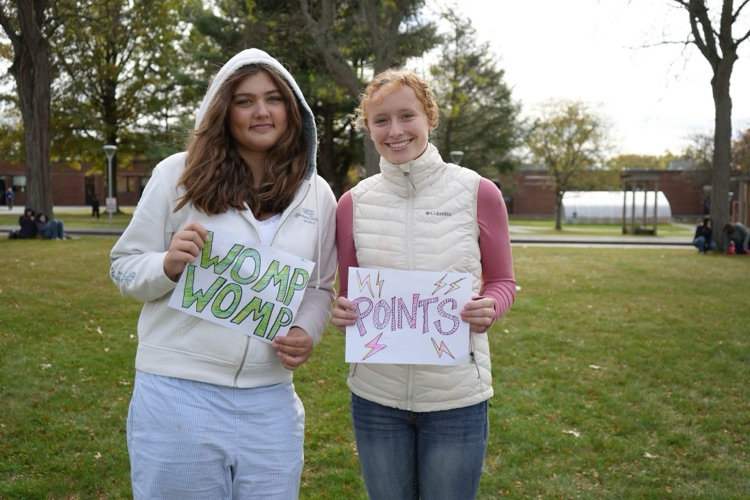 two students cheering on players with signs reading womp womp and points