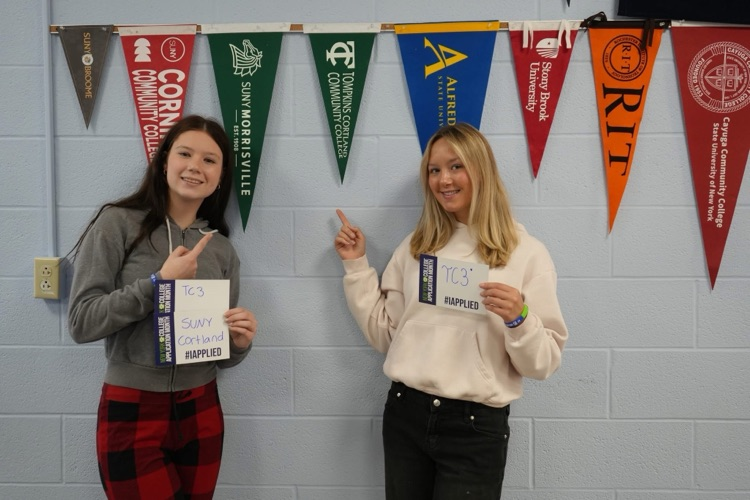 Two CTE students smiling holding #IAPPLIED cards with names of colleges on it