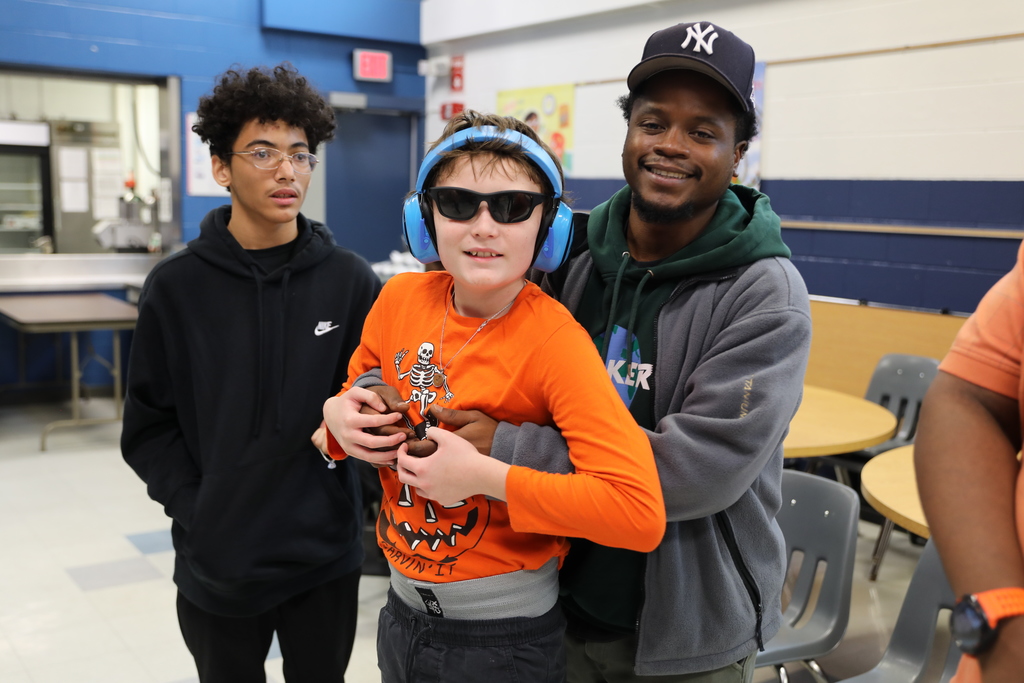 A student posing for camera as they are held up by an adult