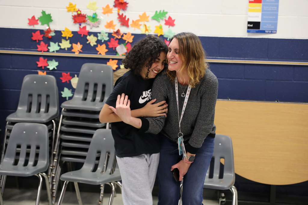 A student and an adult hugging and laughing