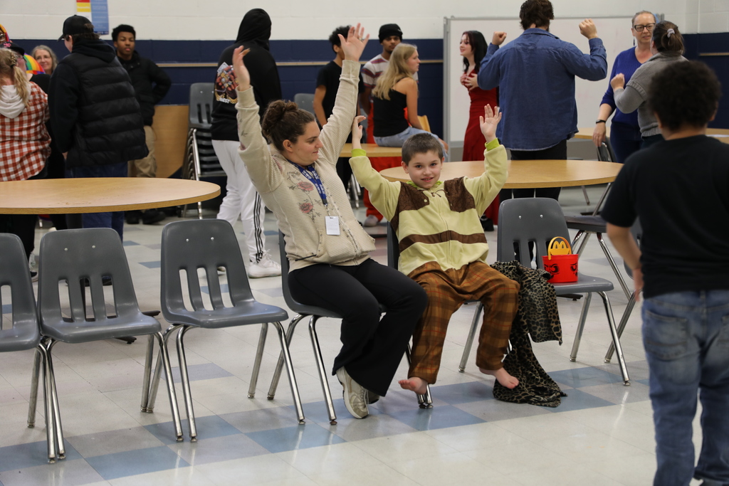 A student and an adult raising theirs hands for a dance