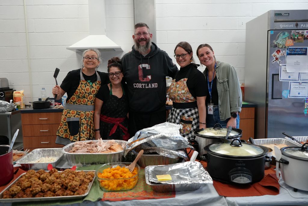 Staff posing for a photo with all the thanksgiving food