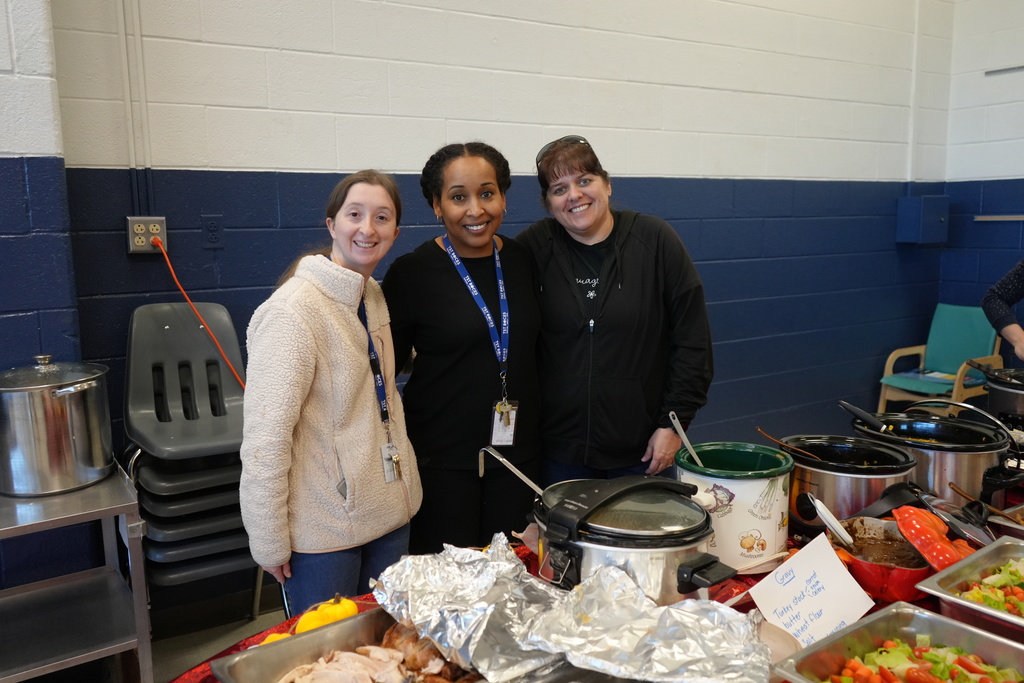 Staff posing for a photo by all the thanksgiving food