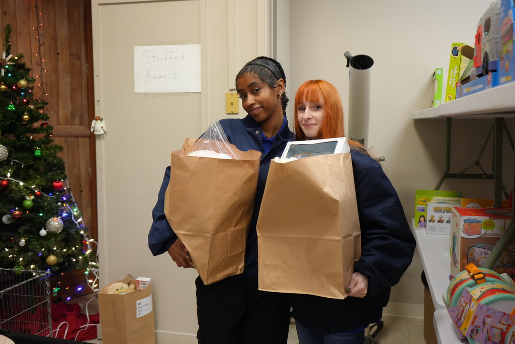 two students holding up their bags of gifts