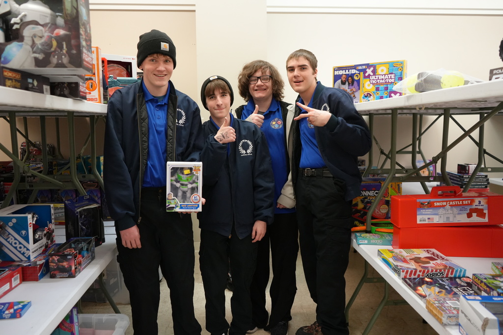 Four students posing for a picture and holding up a gift