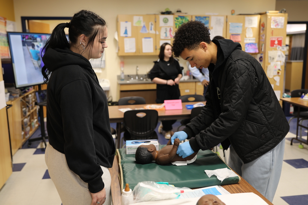 a current student showing a potential new student how to change a baby's diaper