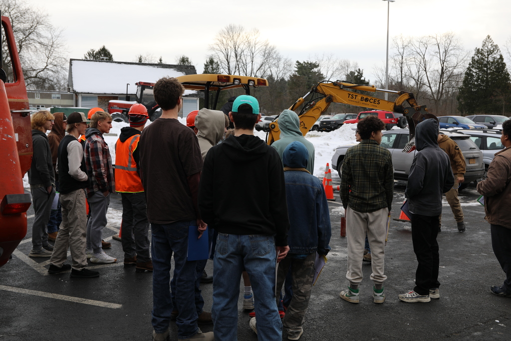 a large group of students watching the operation of heavy equipment 
