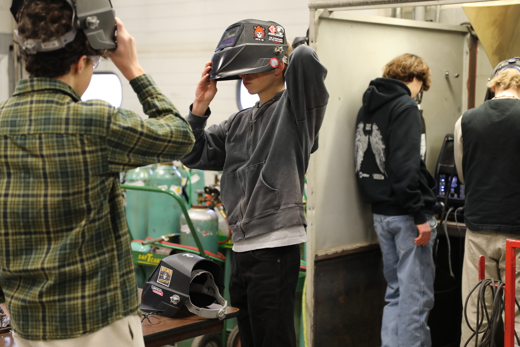 two potential new students putting up welding masks/helmets