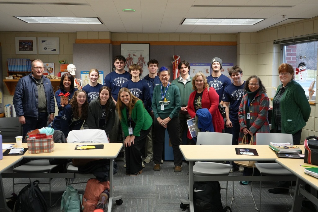 A group of New Visions Exercise and Health Sciences students, instructors, administrators, and Board of Education members pose together inside a classroom at Ithaca College.