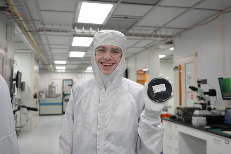 new visions engineering student in clean room at Cornell NanoScale Facility holding wafer