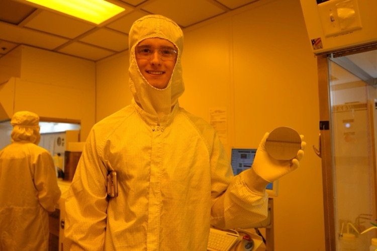 new visions engineering student in clean room at Cornell NanoScale Facility smiling with wafer