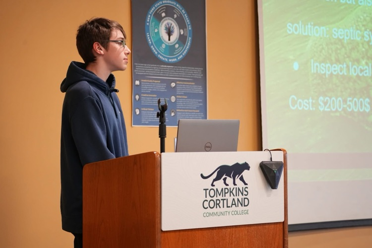 Student presenting at podium with slide about HABs