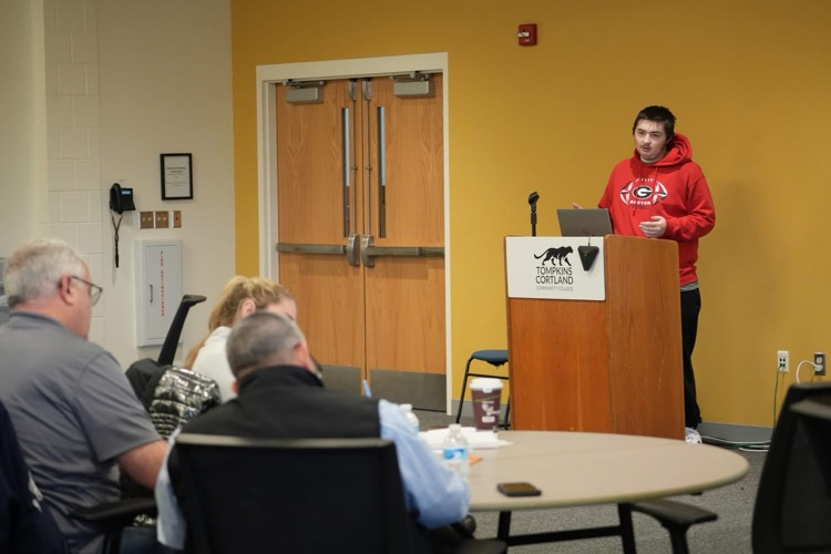 Student presenting at podium with slide about HABs