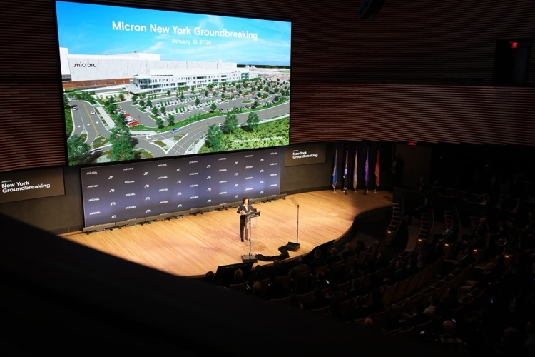 A large screen displays a rendering of Micron’s planned New York semiconductor facility during the Micron New York Groundbreaking event on January 16, 2026. governor Kathy Hochul speaks to audience