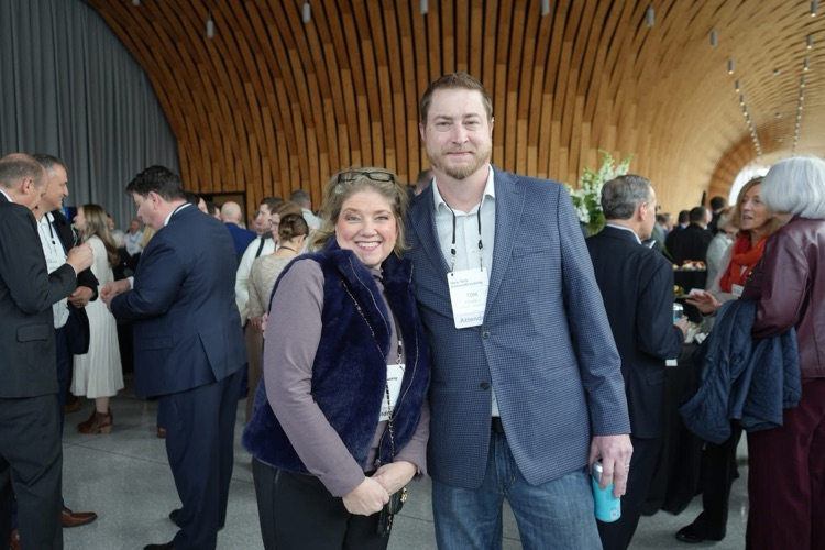 Cindy Walter poses with Cornell NanoScale Facility Workforce Development Program Manager Thomas Pennell inside the event space, surrounded by other attendees networking.