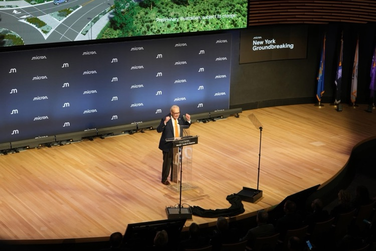 U.S. Senate Majority Leader Chuck Schumer speaks energetically at the podium on the Micron New York Groundbreaking stage.