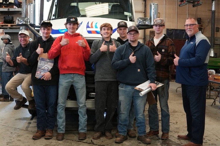 Heavy Equipment students meet with industry partners while equipment and tools are visible in the classroom.