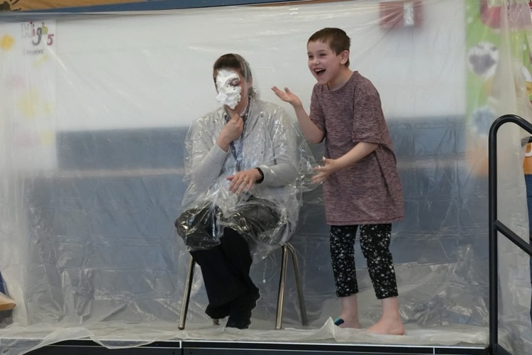 student pies staff member and laughs toward crowd