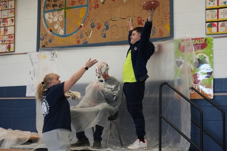 student pies staff and holds hands over head in a winning pose