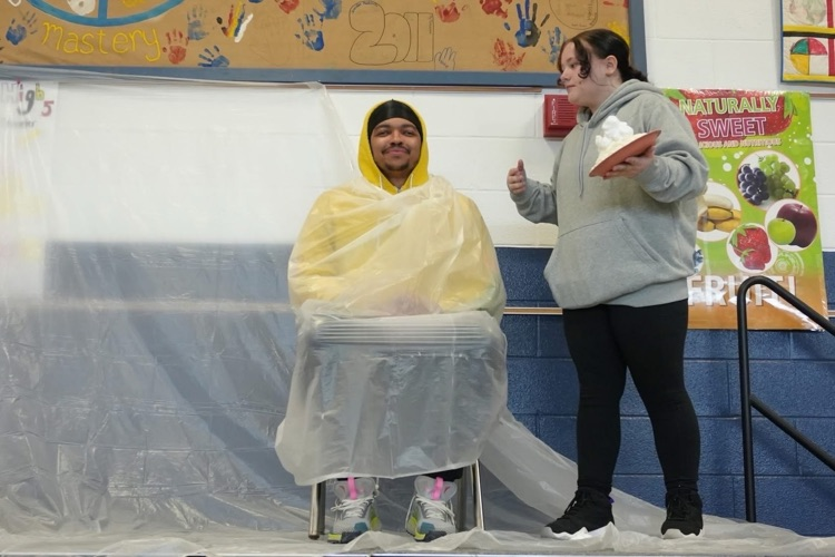 student comes toward staff member with a big whip cream pie in hand