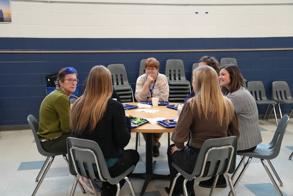 Board members and administrators sit together at a round table in the Smith School cafeteria, sharing lunch and conversation.