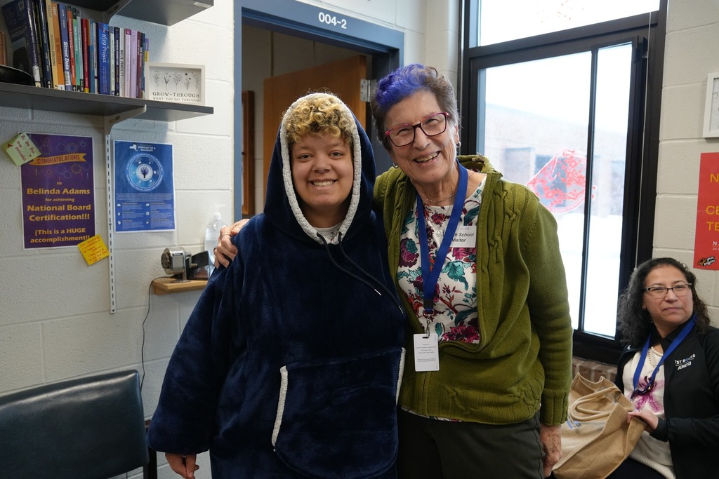 A smiling student stands next to a BOE member in  Smith School during the Board of Education visit.