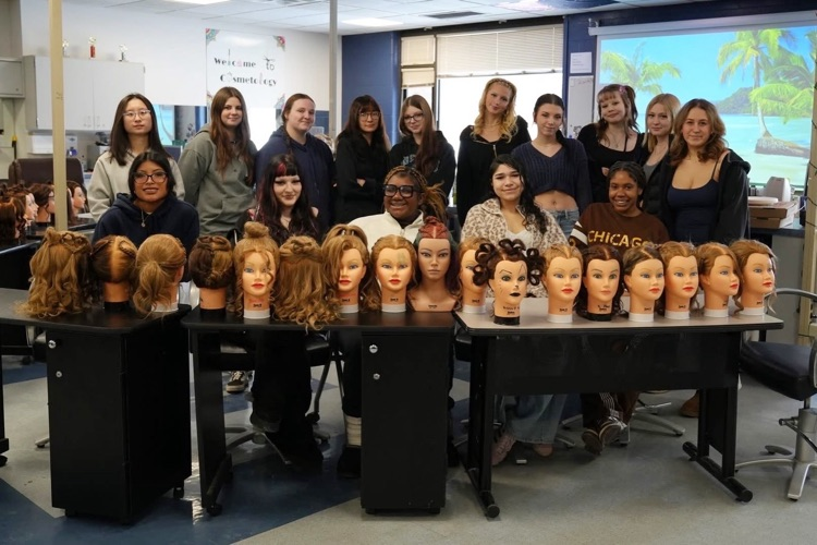   Cosmetology seniors smile and showcase their manikin heads with Valentine themed hairstyles featuring heart designs and braids