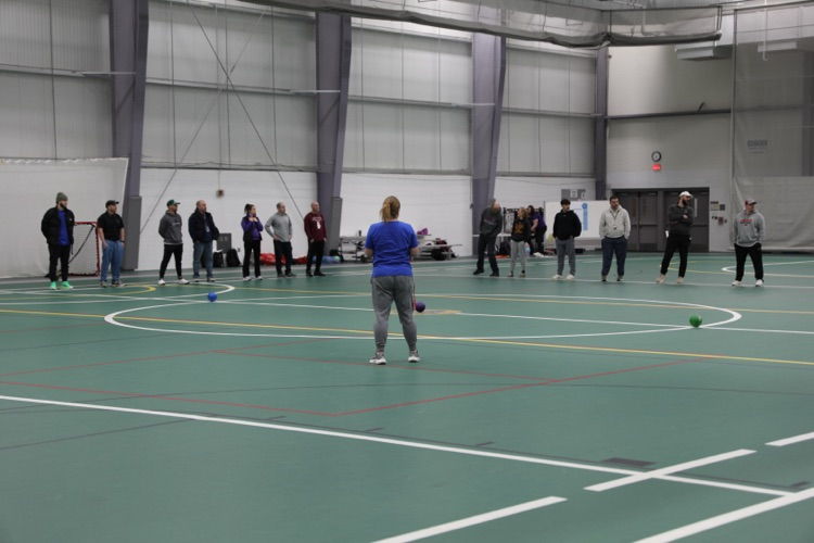  A group of physical education educators stand in a large indoor gym space, participating in an interactive activity as part of the professional development day.