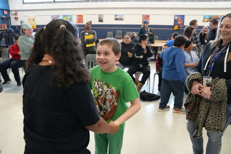 two students holding hands and dancing together at the St. Patty’s Day Dance in the Smith School Cafeteria