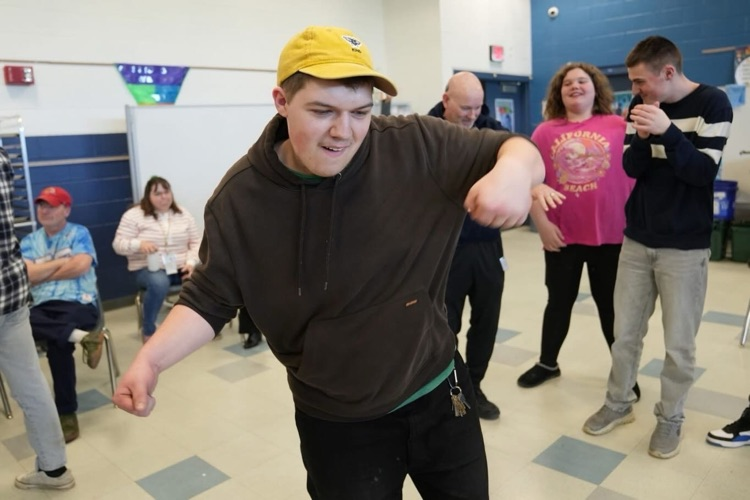One student busting a move on the dance floor, arms raised mid move