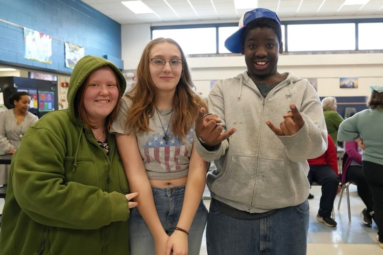 three students at the dance gathered and smile at camera for a picture