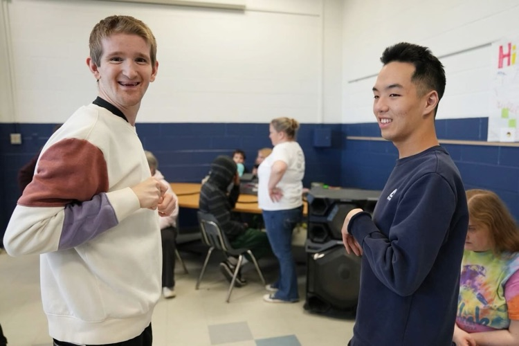 two students are dancing and one looks to the camera smiling