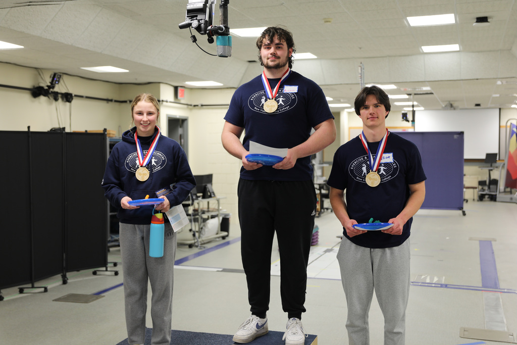 Three students standing to receive their award medals