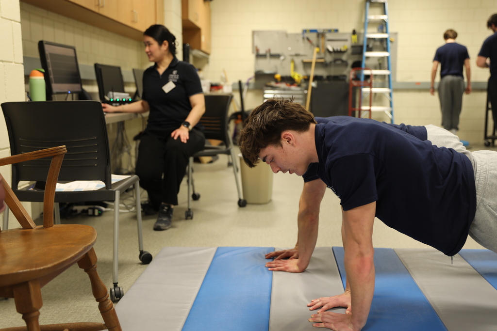two students doing push-ups as they are being monitored