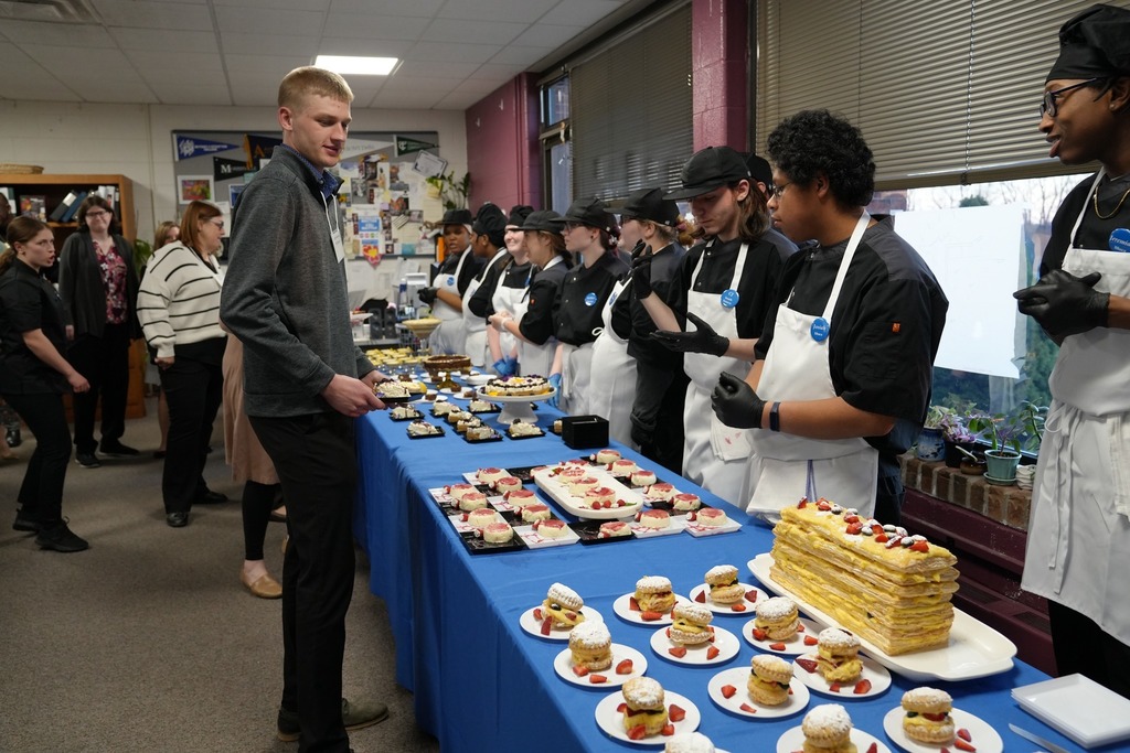 Culinary Arts students serve guests from a dessert table filled with pastries and cakes during the annual dinner.