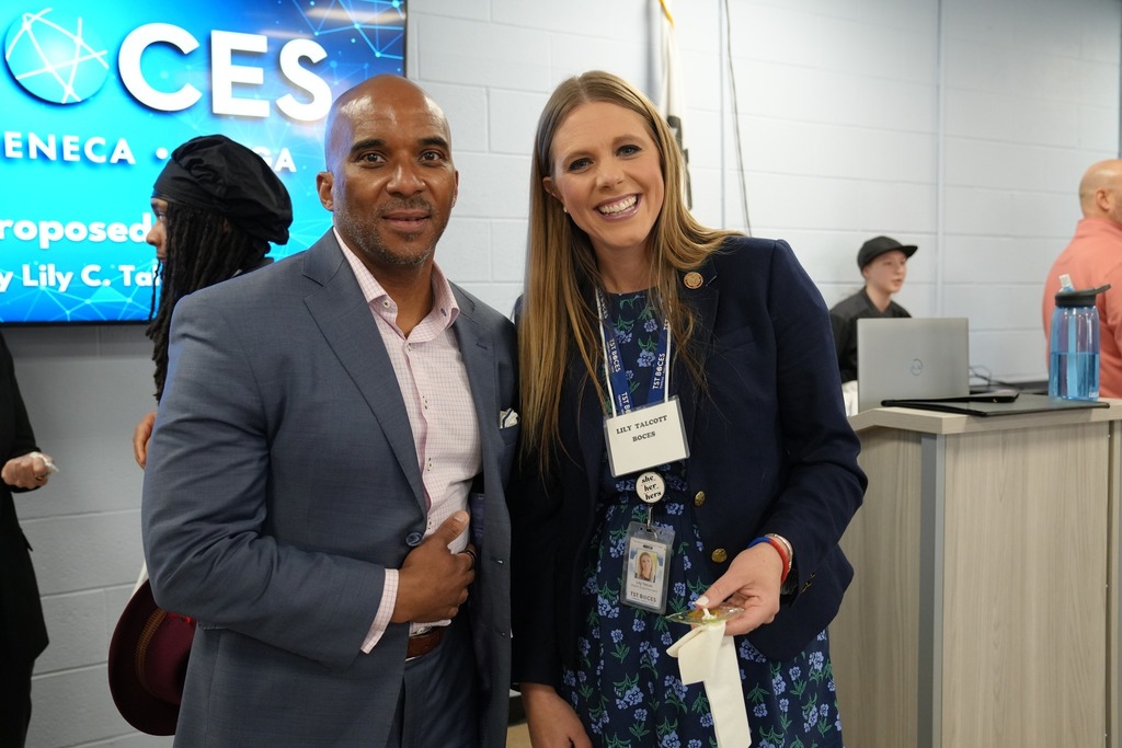 Lily Talcott and Dr. Brown pose together smiling in front of a TST BOCES presentation screen during the annual dinner.