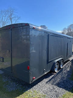 ear angled view of the food trailer showing double doors, serving window panel, and dual axle wheels.